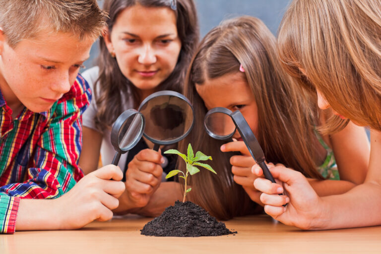 Teacher and students looking at a plant through magnifier