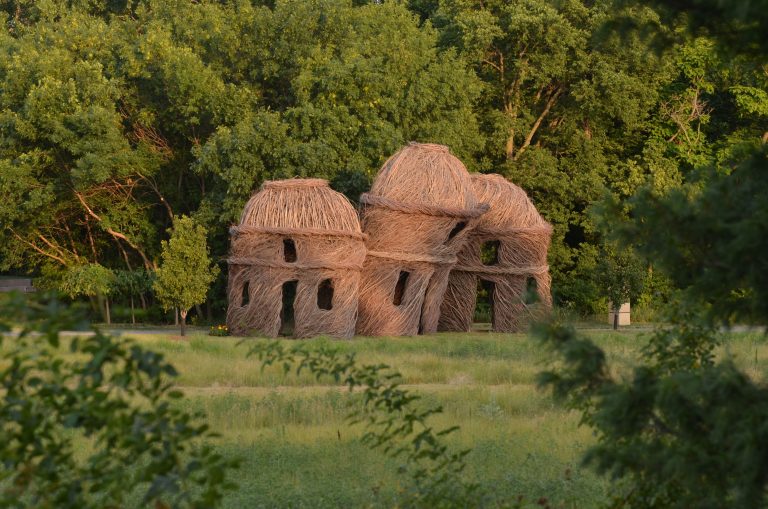 three houses made of a wooden material in front of a forest